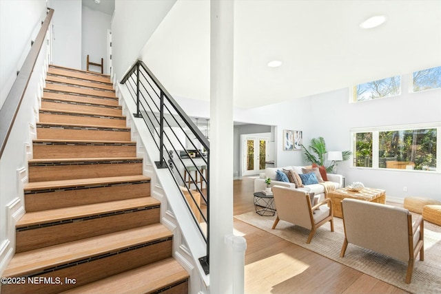 staircase featuring a healthy amount of sunlight, wood finished floors, and a towering ceiling