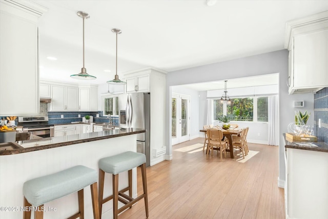 kitchen featuring dark countertops, light wood-style floors, tasteful backsplash, and appliances with stainless steel finishes