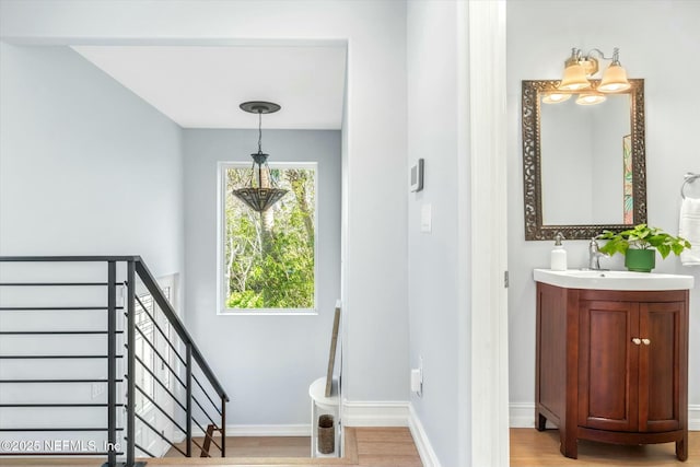 stairs with an inviting chandelier, wood finished floors, and baseboards