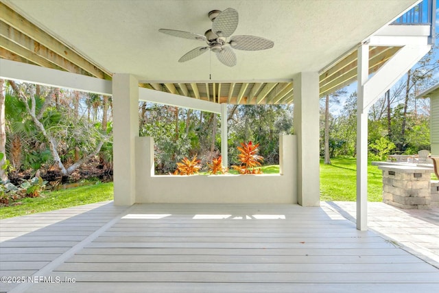 wooden deck featuring a lawn and a ceiling fan