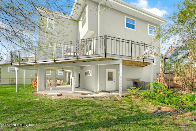 rear view of house with ceiling fan, fence, stucco siding, a yard, and a patio area