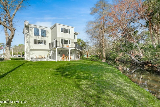 rear view of house with a lawn and stucco siding