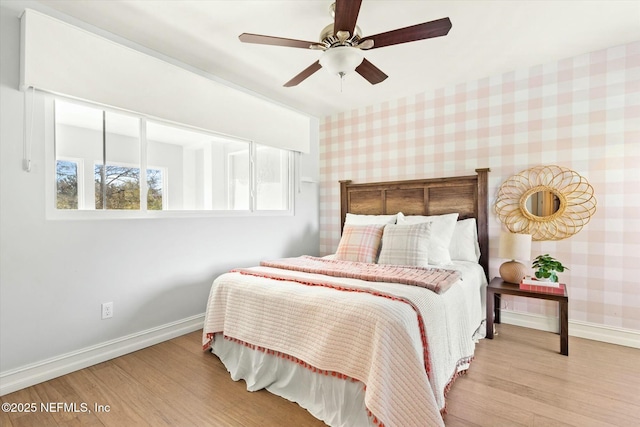 bedroom with wallpapered walls, wood finished floors, baseboards, and ceiling fan