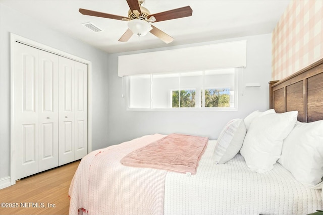 bedroom with a closet, visible vents, ceiling fan, and light wood-style floors