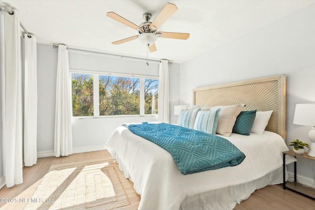 bedroom with ceiling fan, baseboards, and wood finished floors