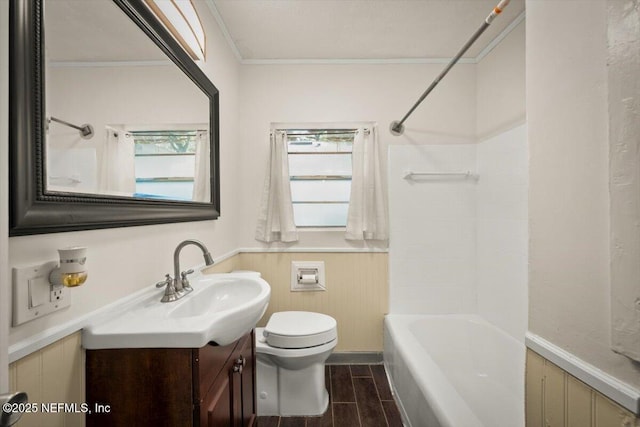 bathroom with wood finish floors, a wainscoted wall, toilet, ornamental molding, and vanity