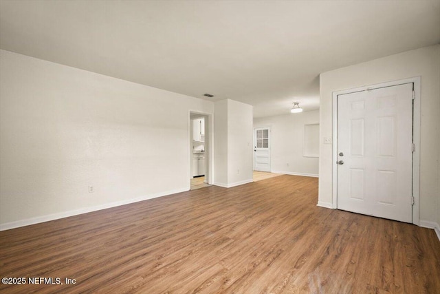 unfurnished living room with baseboards and wood finished floors