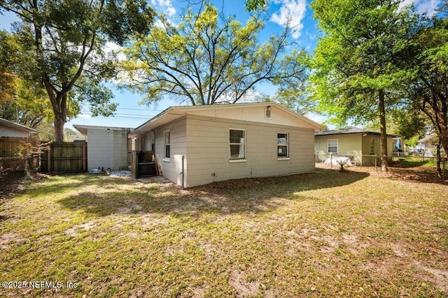 back of house featuring a lawn and fence