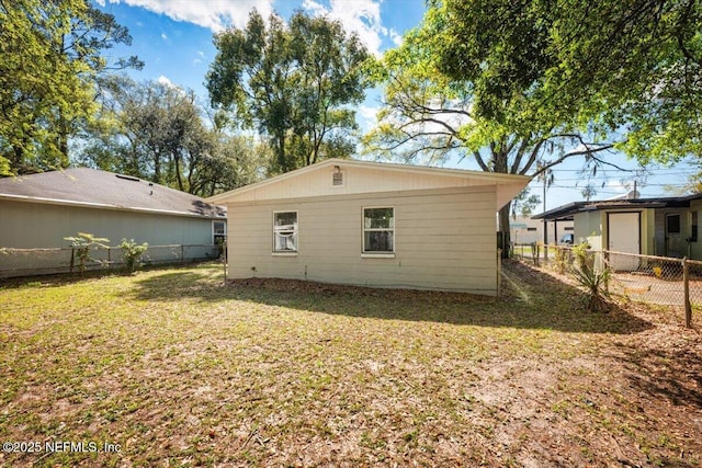 rear view of house featuring a lawn and fence