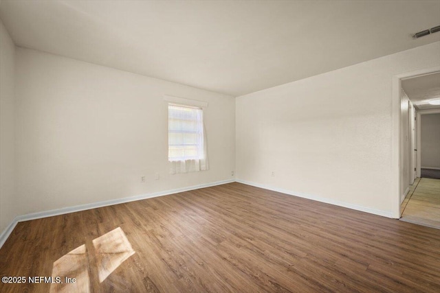 unfurnished room with visible vents, baseboards, and wood finished floors