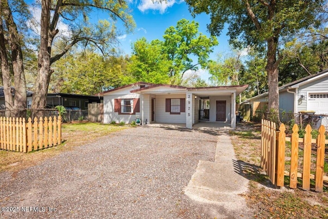 view of front of house featuring a carport, gravel driveway, and fence