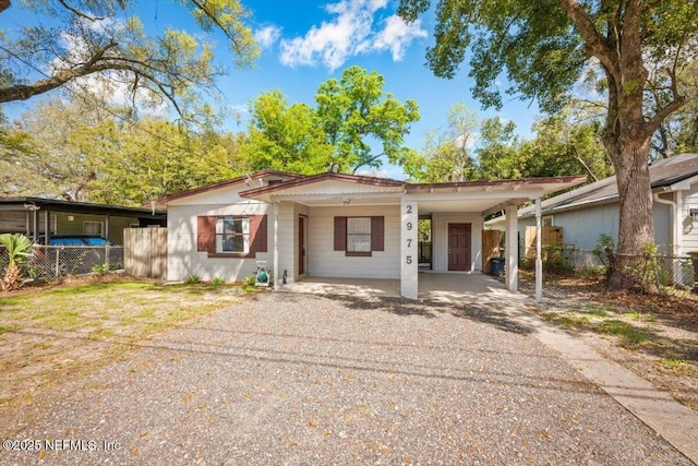 ranch-style home with an attached carport, driveway, and fence