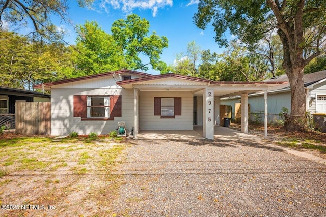 view of front of home featuring an attached carport, driveway, and fence