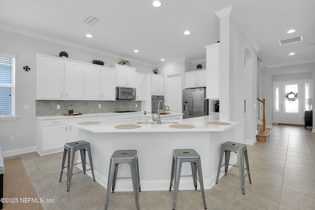 163 Medio Dr, Saint Augustine, FL 32095 - kitchen with visible vents, a breakfast bar, a sink, appliances with stainless steel finishes, and decorative backsplash