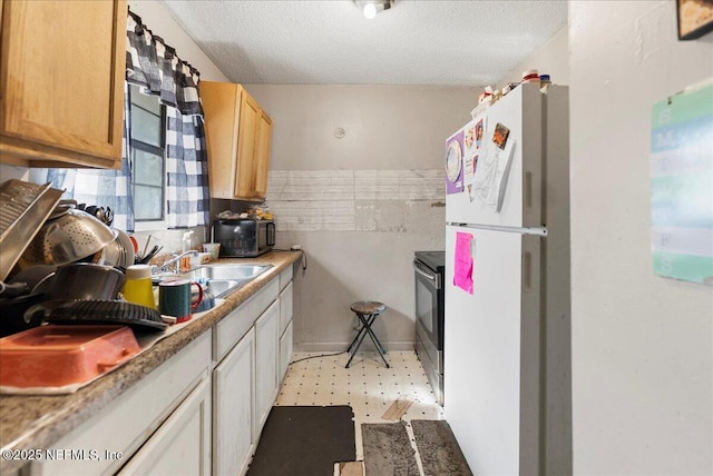 kitchen featuring a sink, a textured ceiling, stainless steel range with electric cooktop, freestanding refrigerator, and light floors