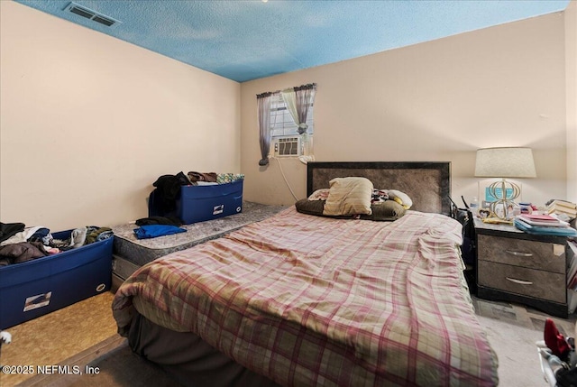 bedroom featuring carpet flooring, visible vents, and a textured ceiling