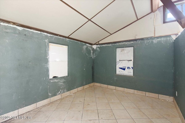 empty room with lofted ceiling and tile patterned floors