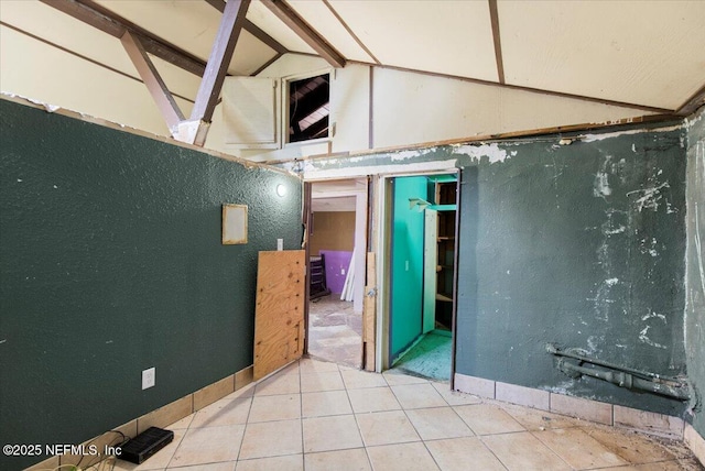 unfurnished room featuring tile patterned floors and lofted ceiling