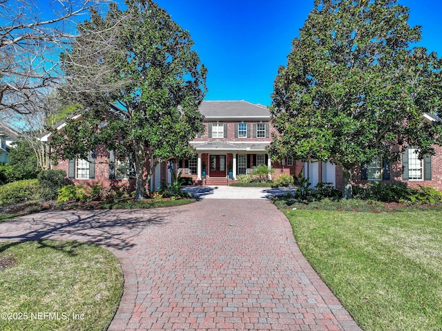 view of front of home featuring decorative driveway, brick siding, a front yard, and french doors