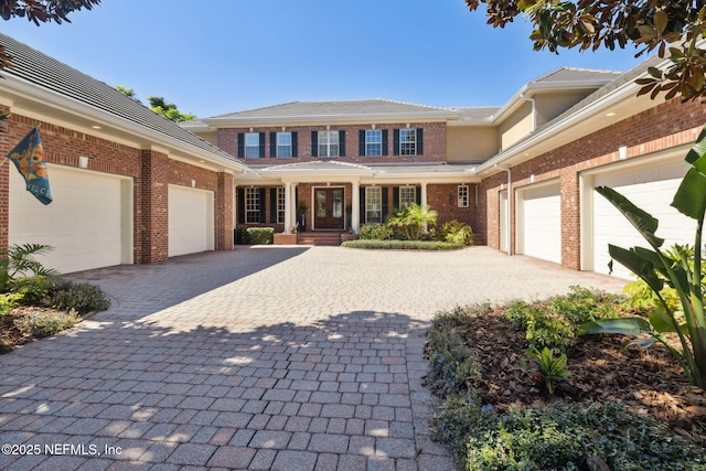 view of front of house featuring brick siding, decorative driveway, and a garage