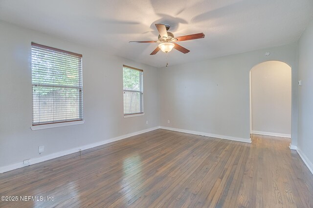 4059 College St, Jacksonville, FL 32205 - empty room with arched walkways, a ceiling fan, baseboards, and dark wood-type flooring