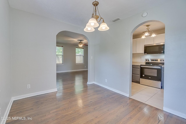 4059 College St, Jacksonville, FL 32205 - kitchen featuring visible vents, arched walkways, white cabinetry, stainless steel appliances, and light wood-style flooring