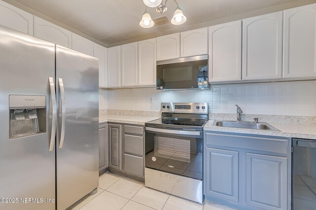 4059 College St, Jacksonville, FL 32205 - kitchen featuring appliances with stainless steel finishes, a sink, light tile patterned floors, light countertops, and white cabinetry