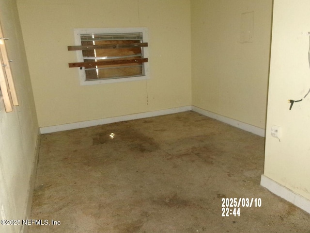 unfurnished room with unfinished concrete floors and baseboards