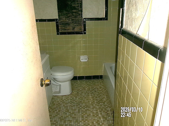 full bath featuring tile patterned flooring, toilet, tile walls, and a bath