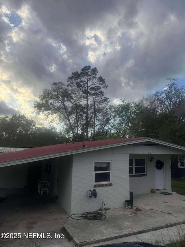 exterior space with concrete block siding and a carport