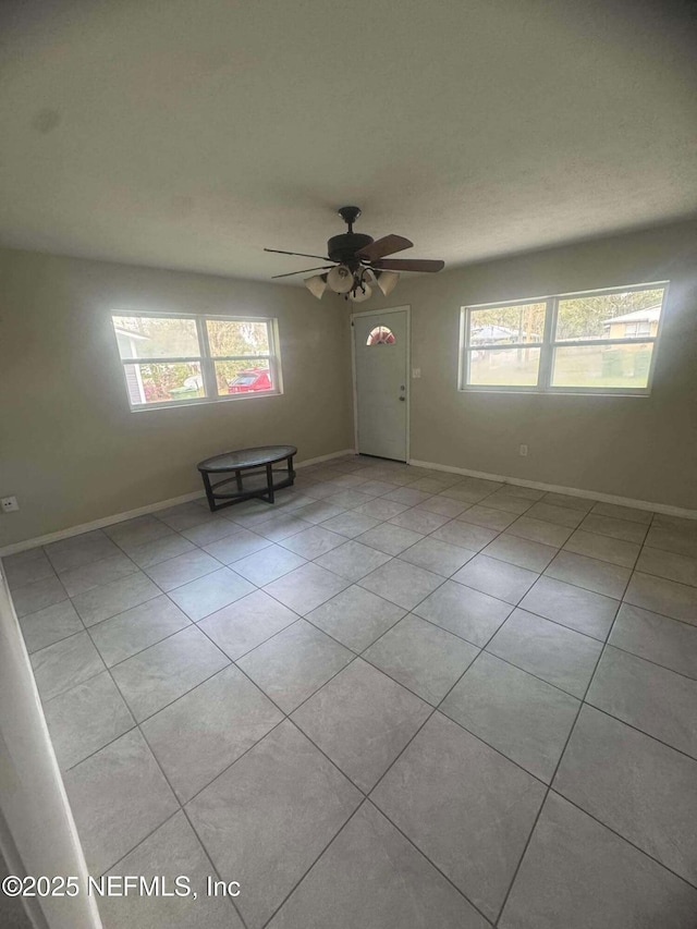 spare room with light tile patterned floors, ceiling fan, and baseboards