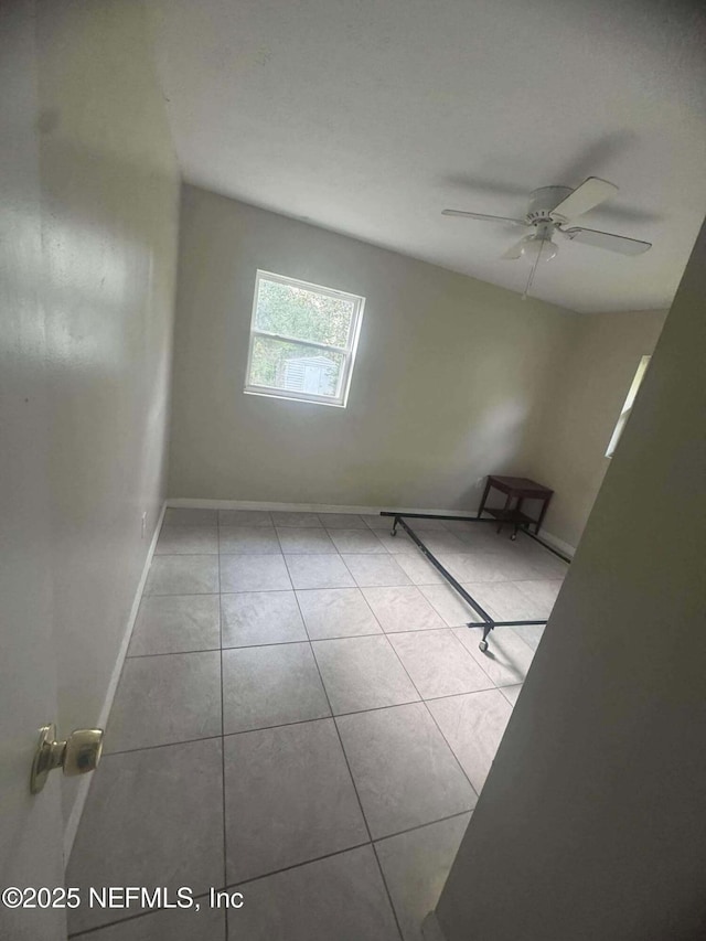 tiled spare room with baseboards and a ceiling fan