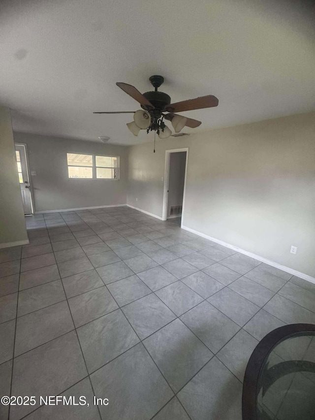 unfurnished room featuring tile patterned flooring, visible vents, baseboards, and ceiling fan