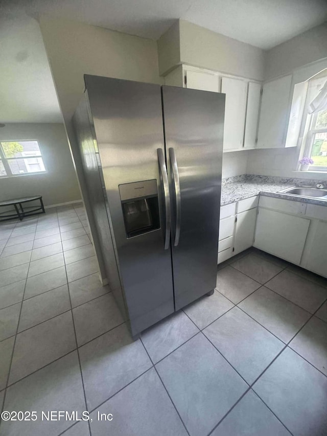 kitchen featuring white cabinetry, light tile patterned flooring, stainless steel refrigerator with ice dispenser, and a sink