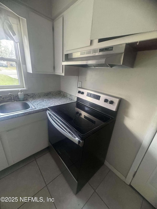 kitchen with stainless steel electric range, a sink, light countertops, white cabinets, and under cabinet range hood