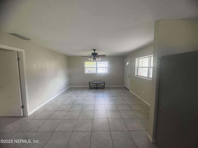 empty room featuring light tile patterned floors, baseboards, visible vents, and ceiling fan