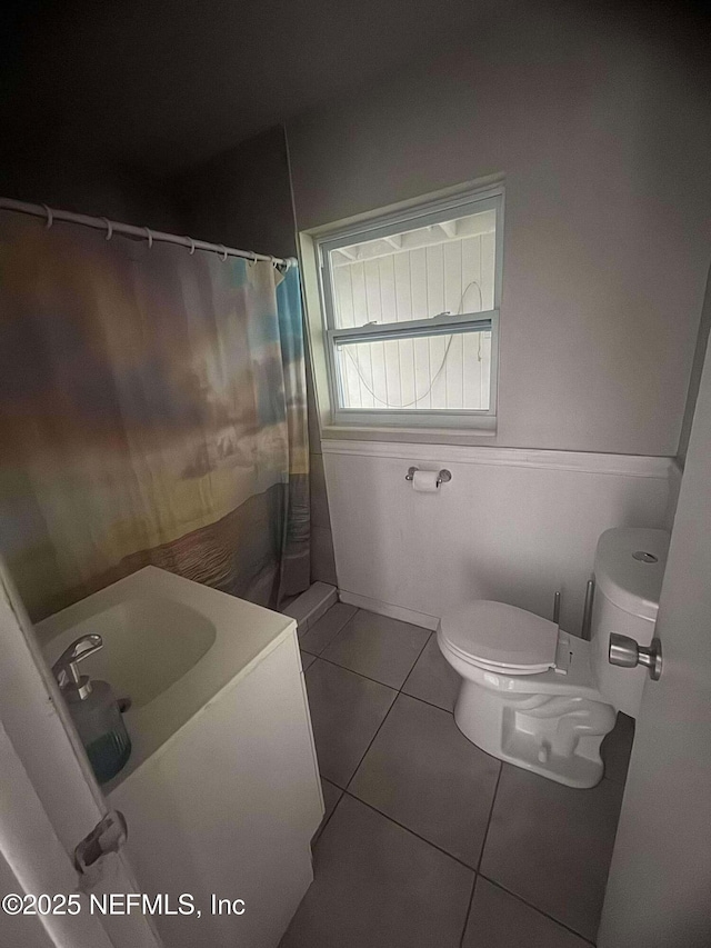 bathroom with tile patterned flooring, toilet, a shower with curtain, and a sink