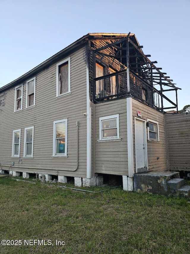 rear view of property featuring a balcony and a lawn