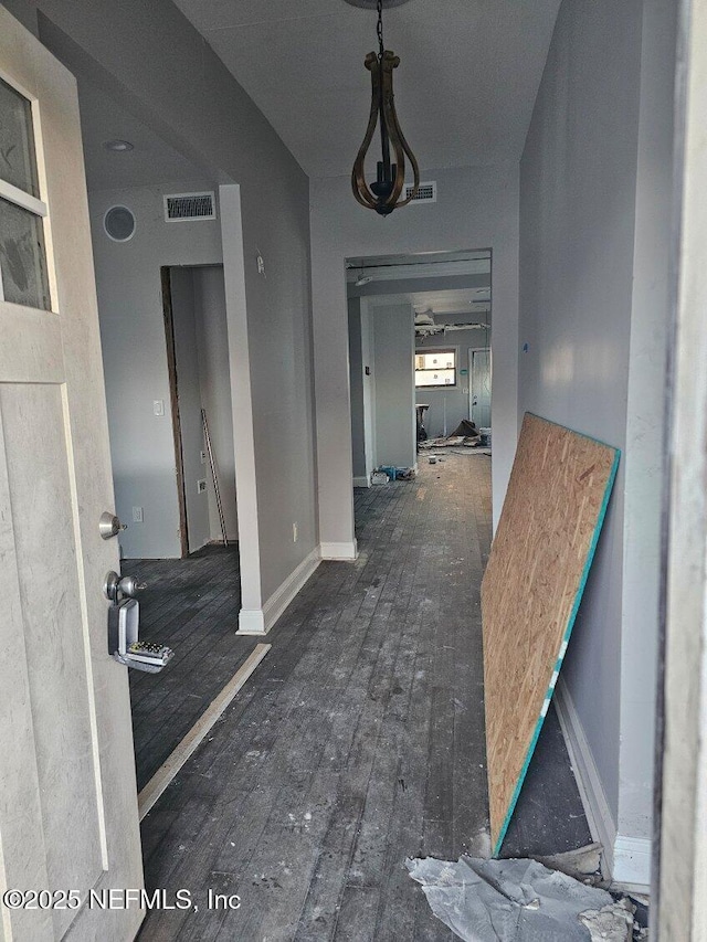 hall featuring visible vents, baseboards, and hardwood / wood-style floors