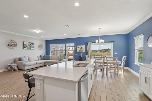 kitchen with light wood finished floors, a sink, an inviting chandelier, white cabinetry, and stainless steel dishwasher