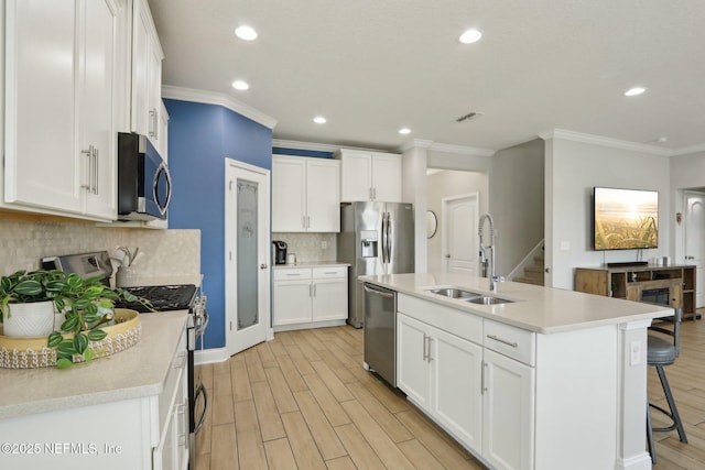 kitchen featuring a breakfast bar, a sink, light wood-style floors, appliances with stainless steel finishes, and white cabinets