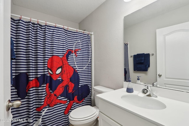 bathroom with vanity, toilet, a textured wall, and a textured ceiling