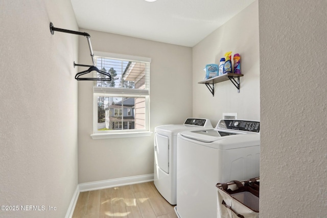 washroom with laundry area, baseboards, light wood-type flooring, and washing machine and clothes dryer