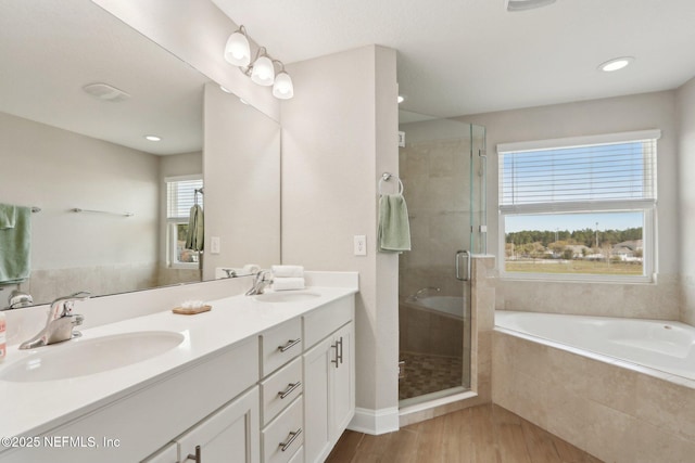 full bath featuring a bath, wood finished floors, a stall shower, and a sink