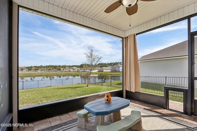 sunroom with a ceiling fan and a water view