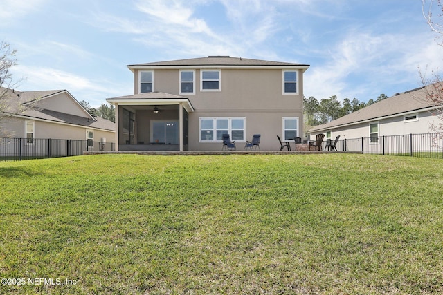 rear view of property featuring a lawn, fence, and stucco siding