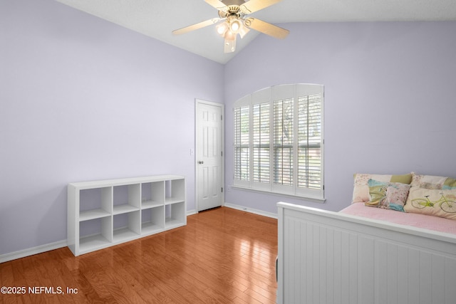 unfurnished bedroom featuring ceiling fan, baseboards, lofted ceiling, and wood finished floors