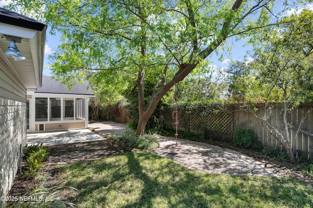 view of yard with a sunroom, a fenced backyard, and a patio area