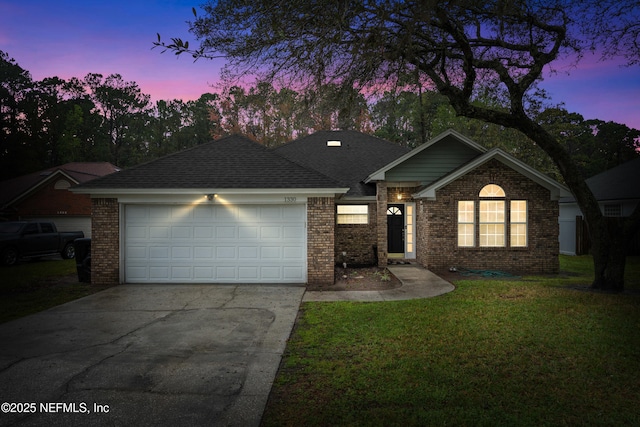 single story home featuring brick siding, a shingled roof, a front lawn, a garage, and driveway