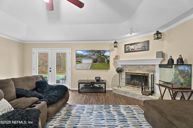 living area with a textured ceiling, wood finished floors, a high end fireplace, french doors, and crown molding